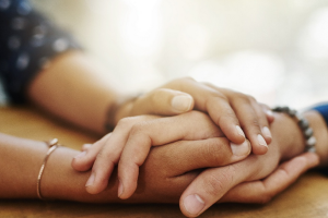 Bild: Ein Mensch hält die Hände eines anderen, Titelbild der Tagung, Quelle: zeppbremen.de